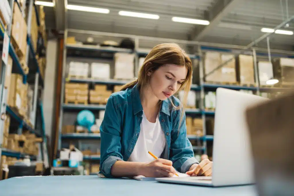 Woman using laptop at warehouse