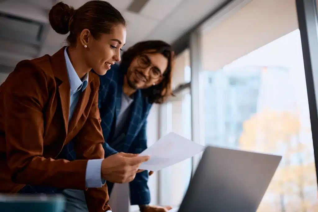 Young businesswoman and her colleague cooperating while working on paperwork in the office.