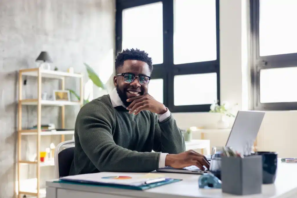 Confident young african american businessman working and smiling at his desk